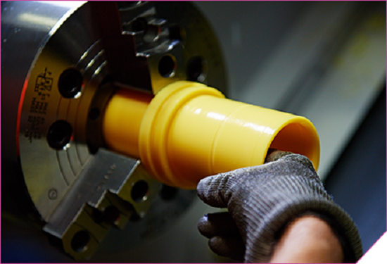 A person operating a CNC machine to cut a yellow tube.