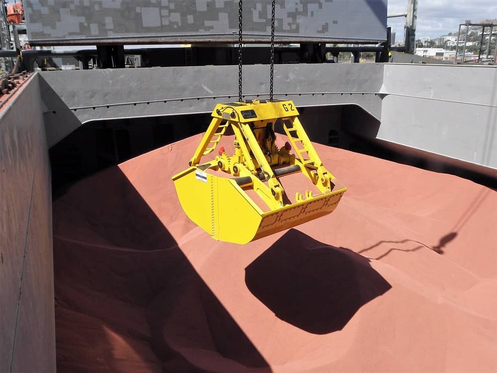 A crane grab lined with UHMWPE operates off a cargo ship.