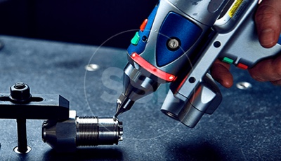 Metalworking in progress: a person carefully drilling a hole in a piece of metal using a drill press.