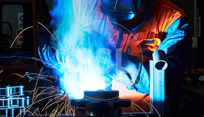 Industrial worker in a factory, using a welding torch to join pieces of metal together.