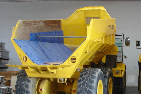A yellow dump truck with blue truck bed liner.