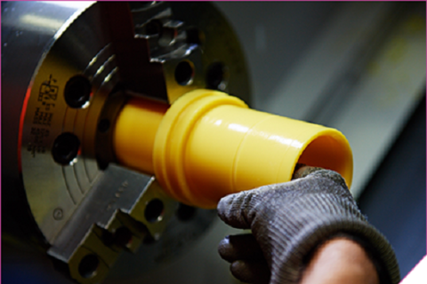 A person operating a CNC machine to cut a yellow tube.