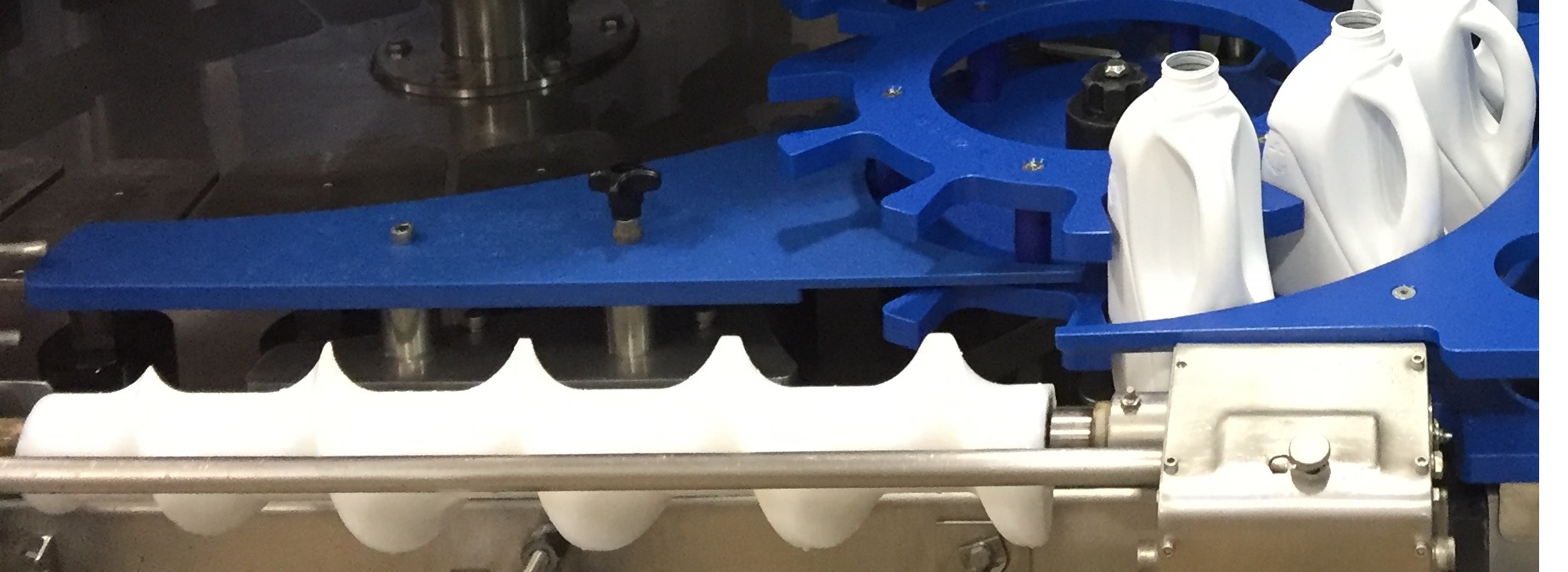 A timing screw guides milk containers into a production line. 